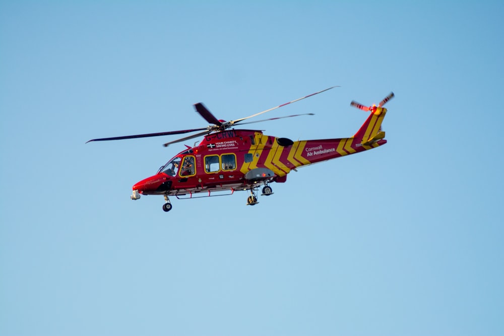 red and yellow helicopter flying in the sky