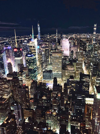 A bustling cityscape at night with illuminated skyscrapers and lively streets.