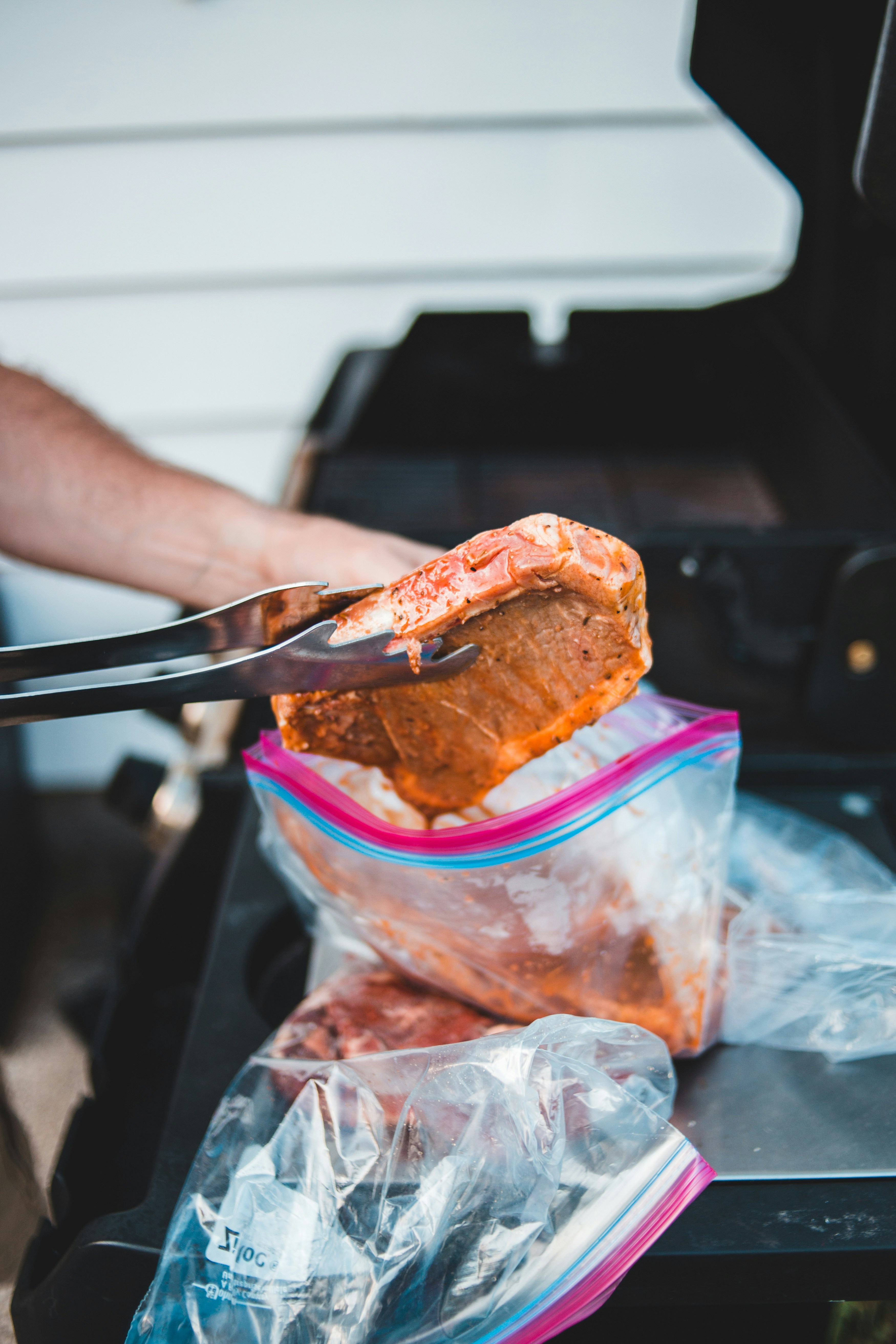 Shredded chicken being placed into clear freezer bags with tongs`