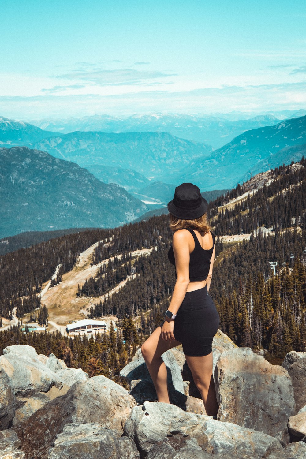 Mujer con camiseta sin mangas negra y pantalones cortos negros de pie en la Montaña Rocosa durante el día