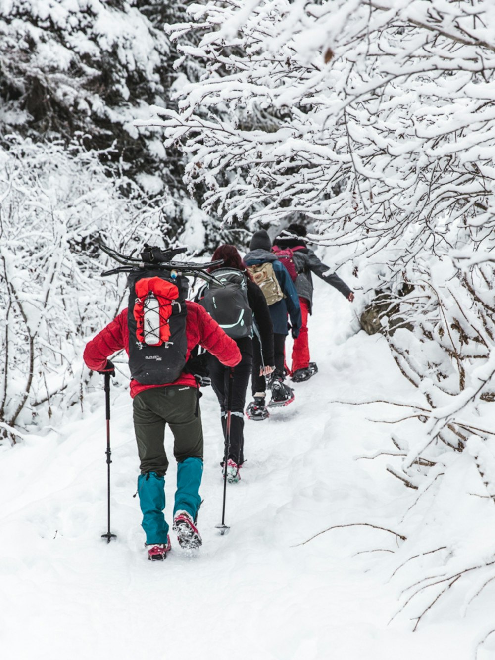 2 persone in giacca rossa e pantaloni neri in piedi su un terreno innevato durante il giorno