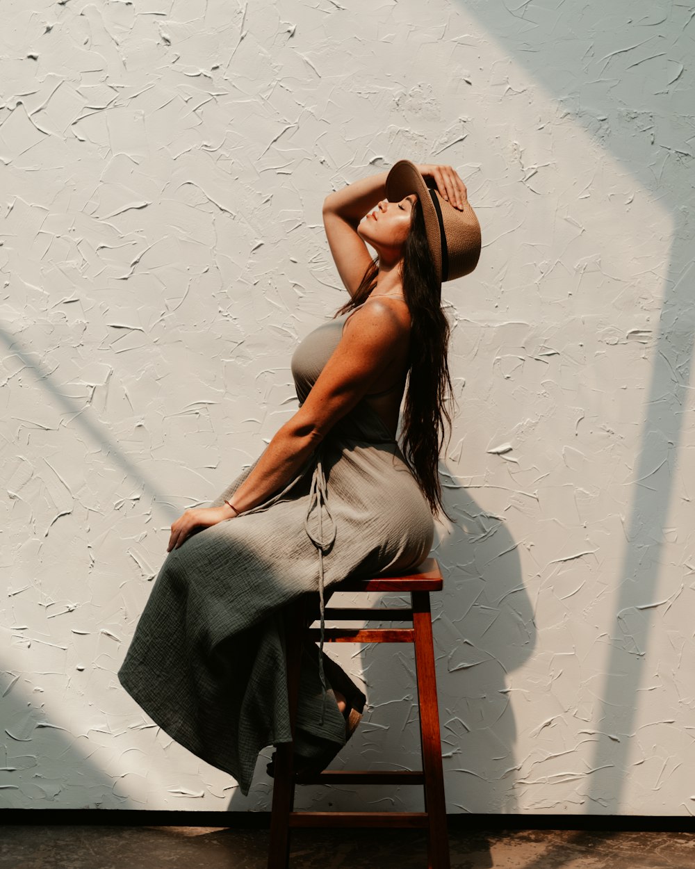 woman in gray spaghetti strap dress sitting on brown wooden chair