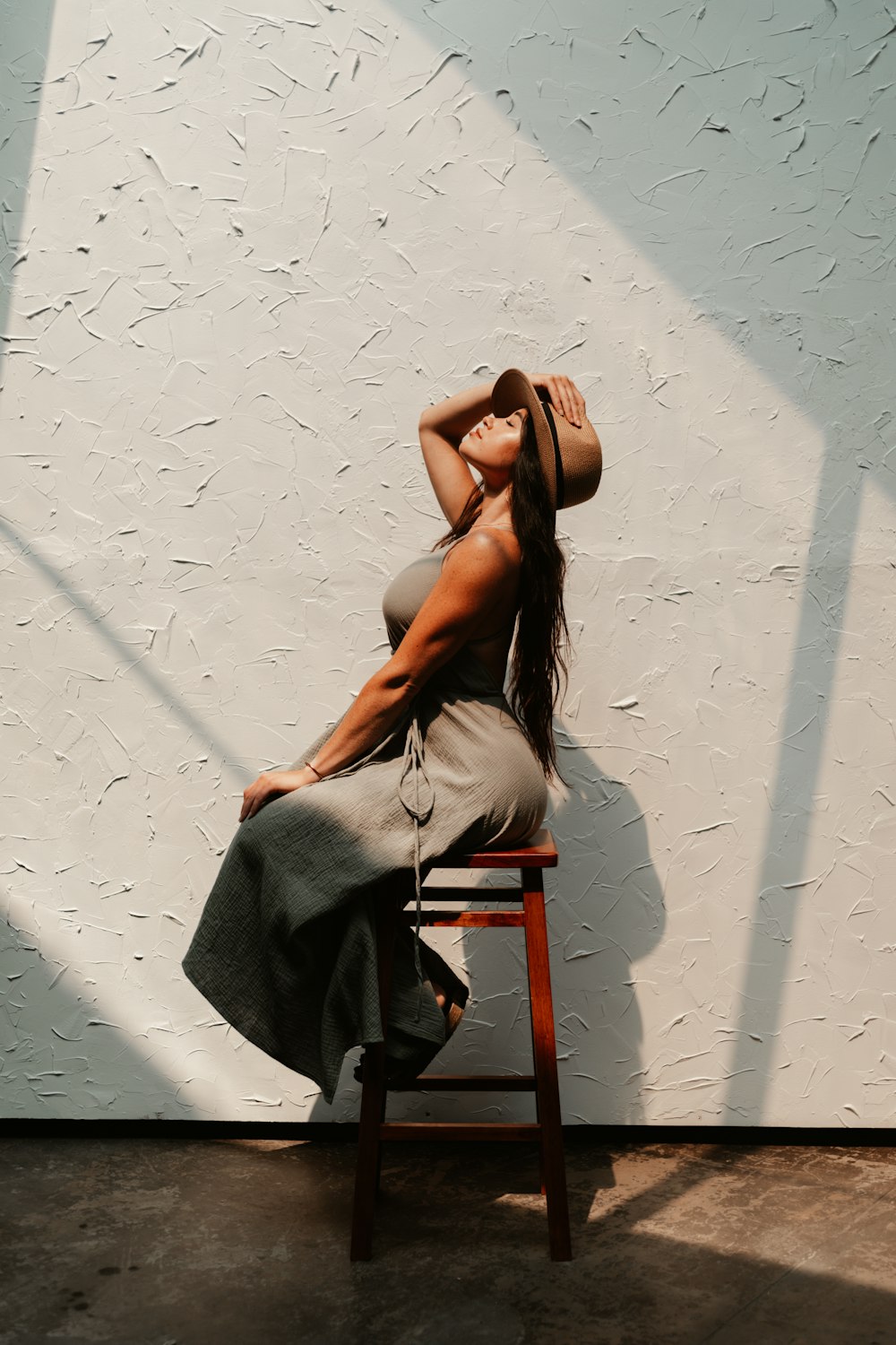 femme en débardeur blanc assise sur une chaise en bois marron