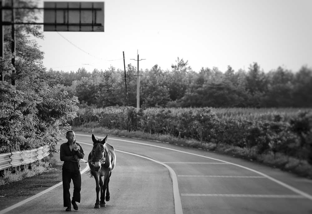 grayscale photo of 2 men riding horses on road