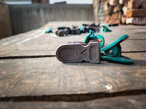 Close-up of a sleek, flexible hair clip held gently between fingers, highlighting its smooth curves and soft khaki green tone.