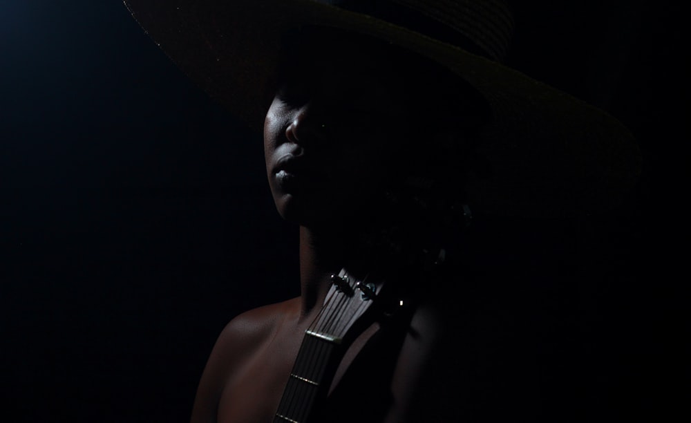 man wearing black hat holding guitar