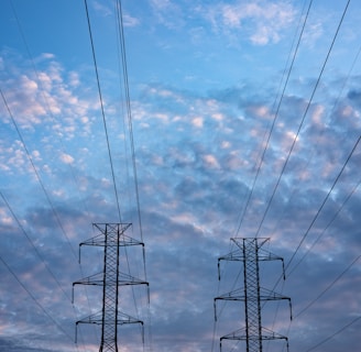 black electric tower under blue sky and white clouds during daytime