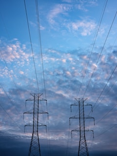 black electric tower under blue sky and white clouds during daytime