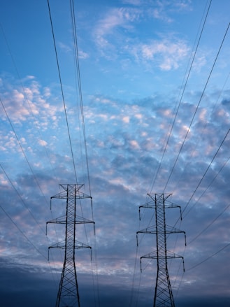 black electric tower under blue sky and white clouds during daytime