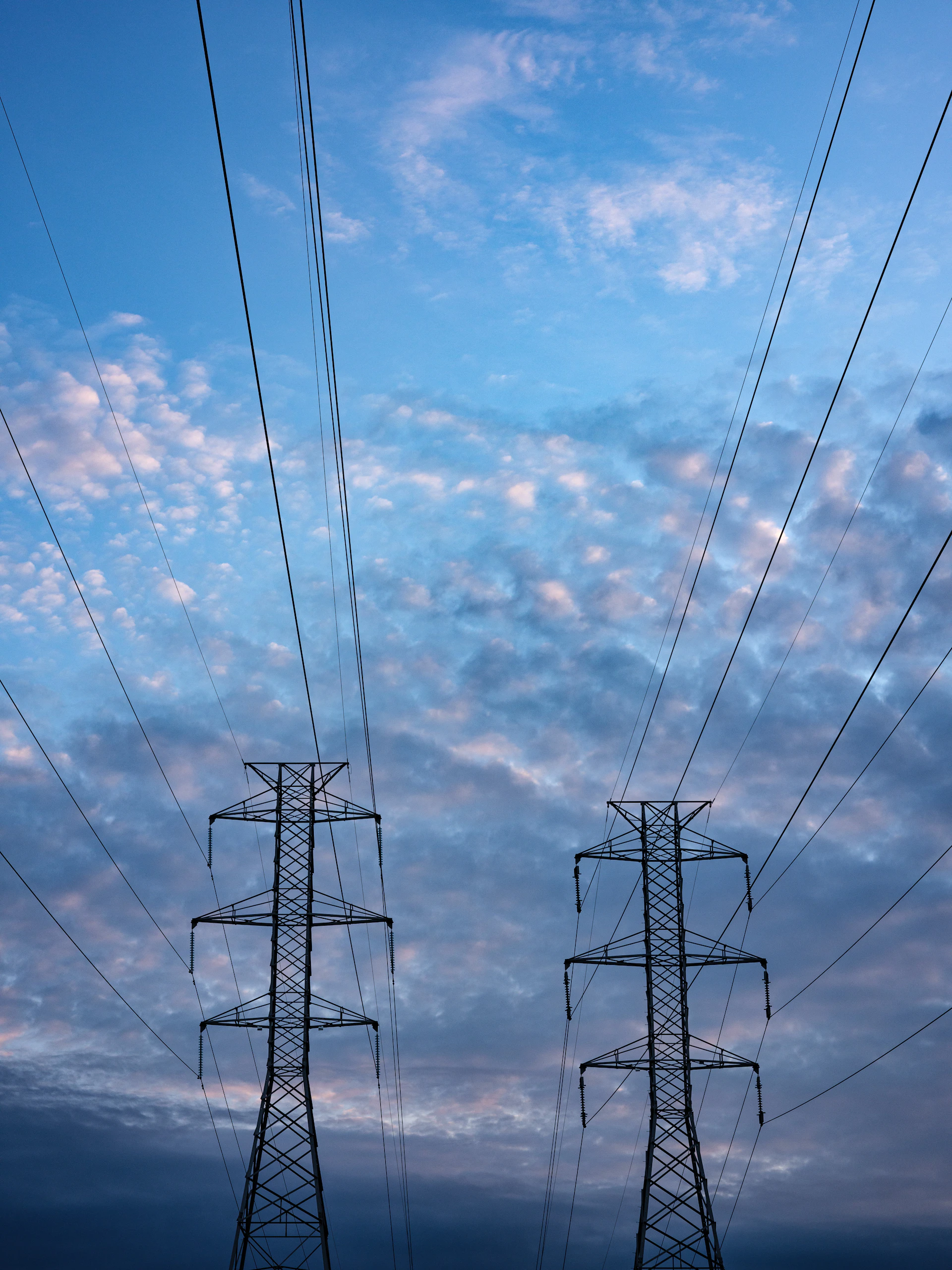 Black electrical transmission tower under a blue sky representing Berjos Limited project works