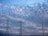 Two transmission towers and a radio antenna rise against a backdrop of an evening or early morning sky, filled with soft, scattered clouds. The sky transitions from light to darker shades of blue, creating a tranquil scene.