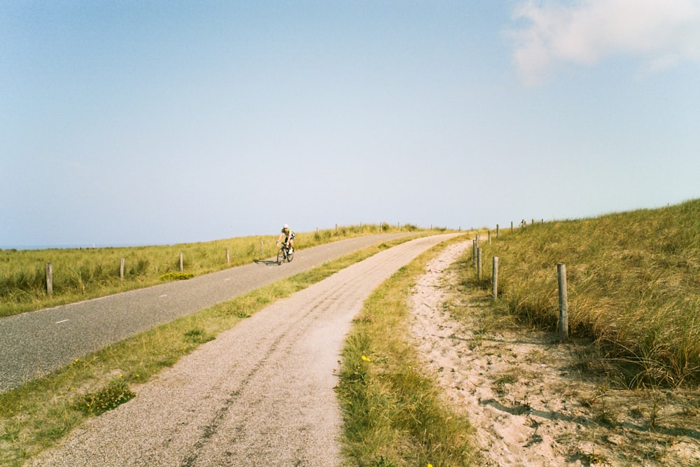 person riding bicycle on dirt road during daytime