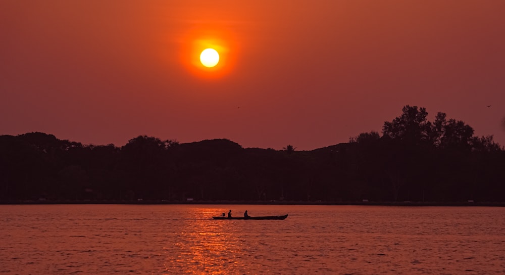 silhouette of boat on sea during sunset