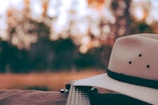 Close-up of a musician playing an acoustic guitar with a cowboy hat nearby.