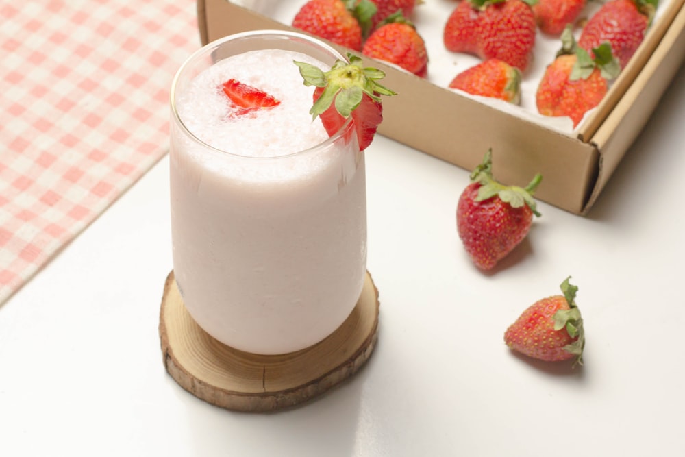 strawberry and white liquid in clear drinking glass