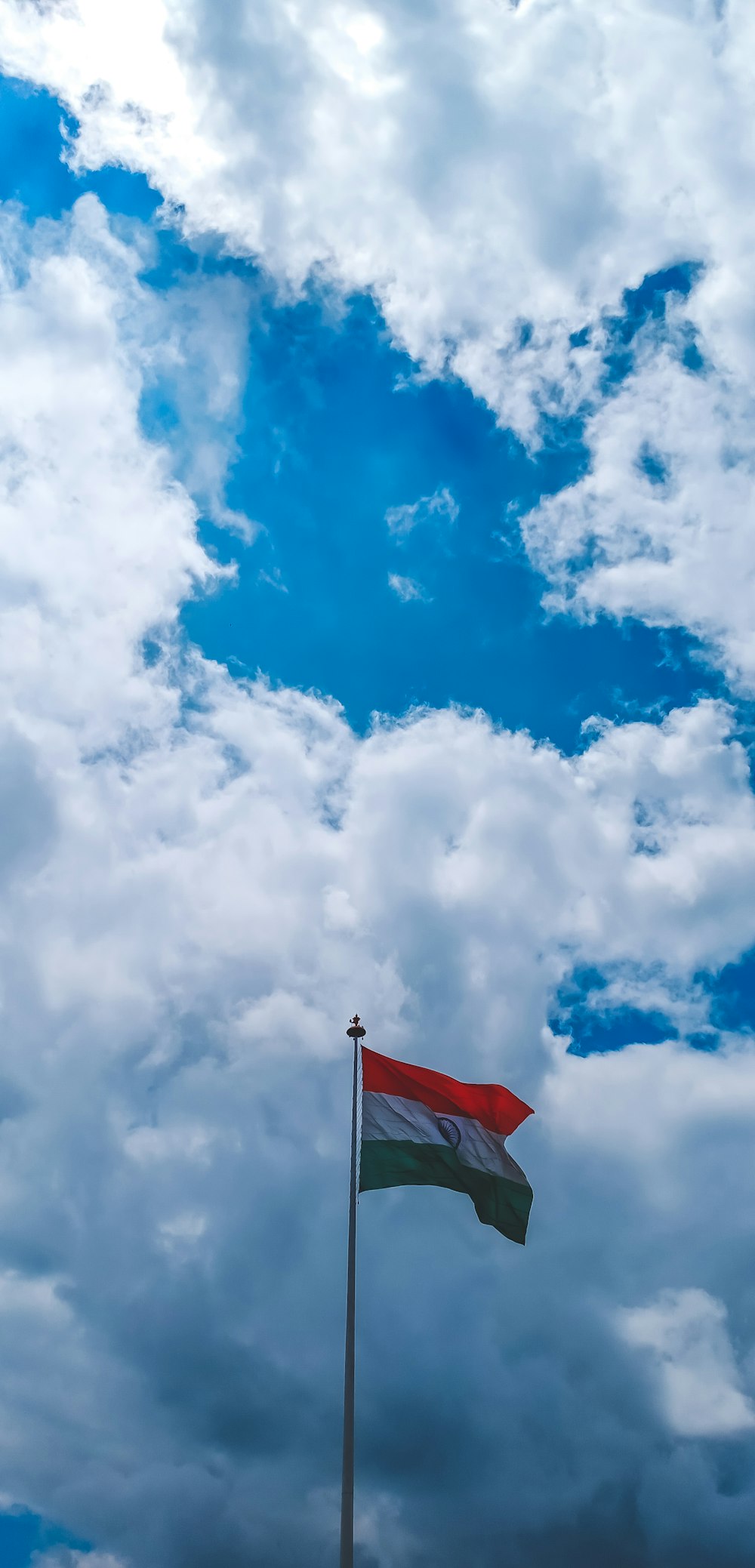 red and white flag under blue sky and white clouds during daytime
