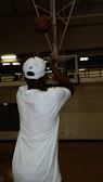 Close-up of a player shooting a jump shot with determination inside a gym.