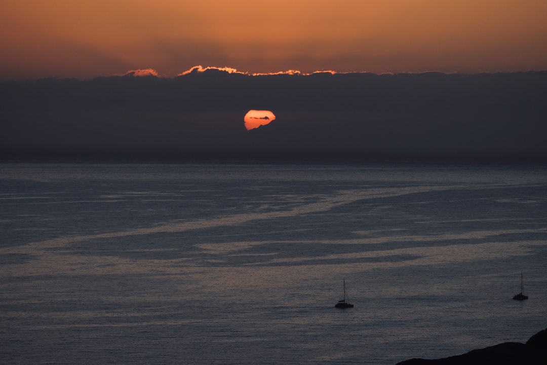 red hot air balloon flying over the clouds during sunset