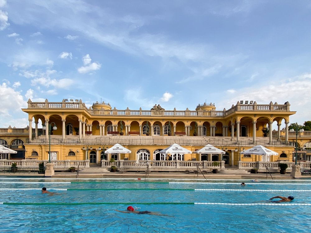 persone in piscina vicino a un edificio in cemento beige durante il giorno