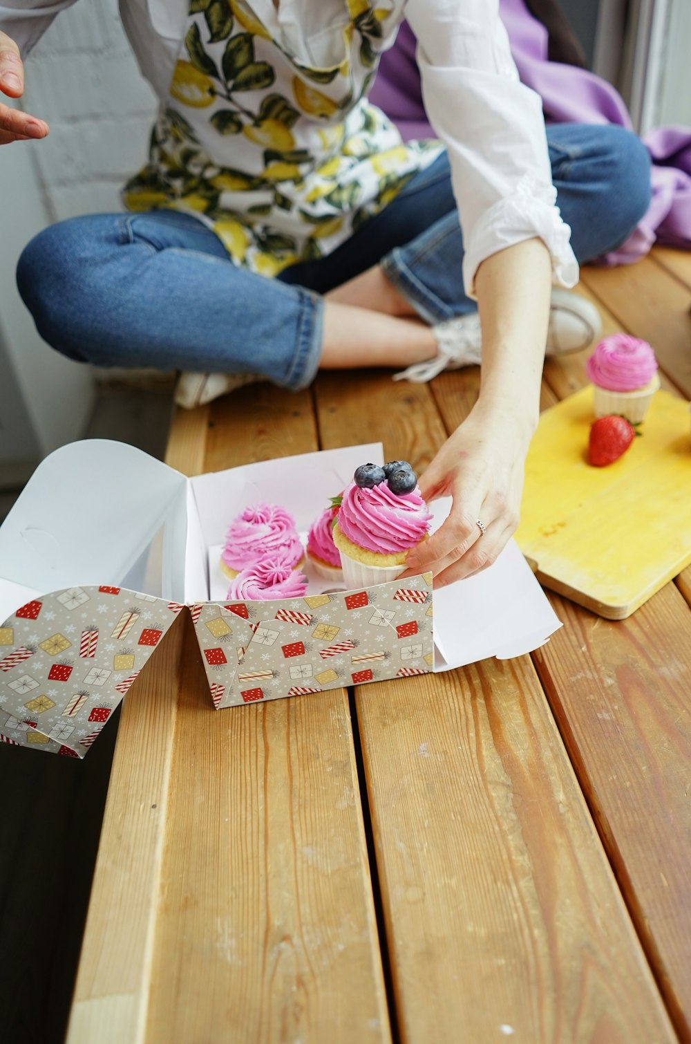 person holding pink and white cupcake