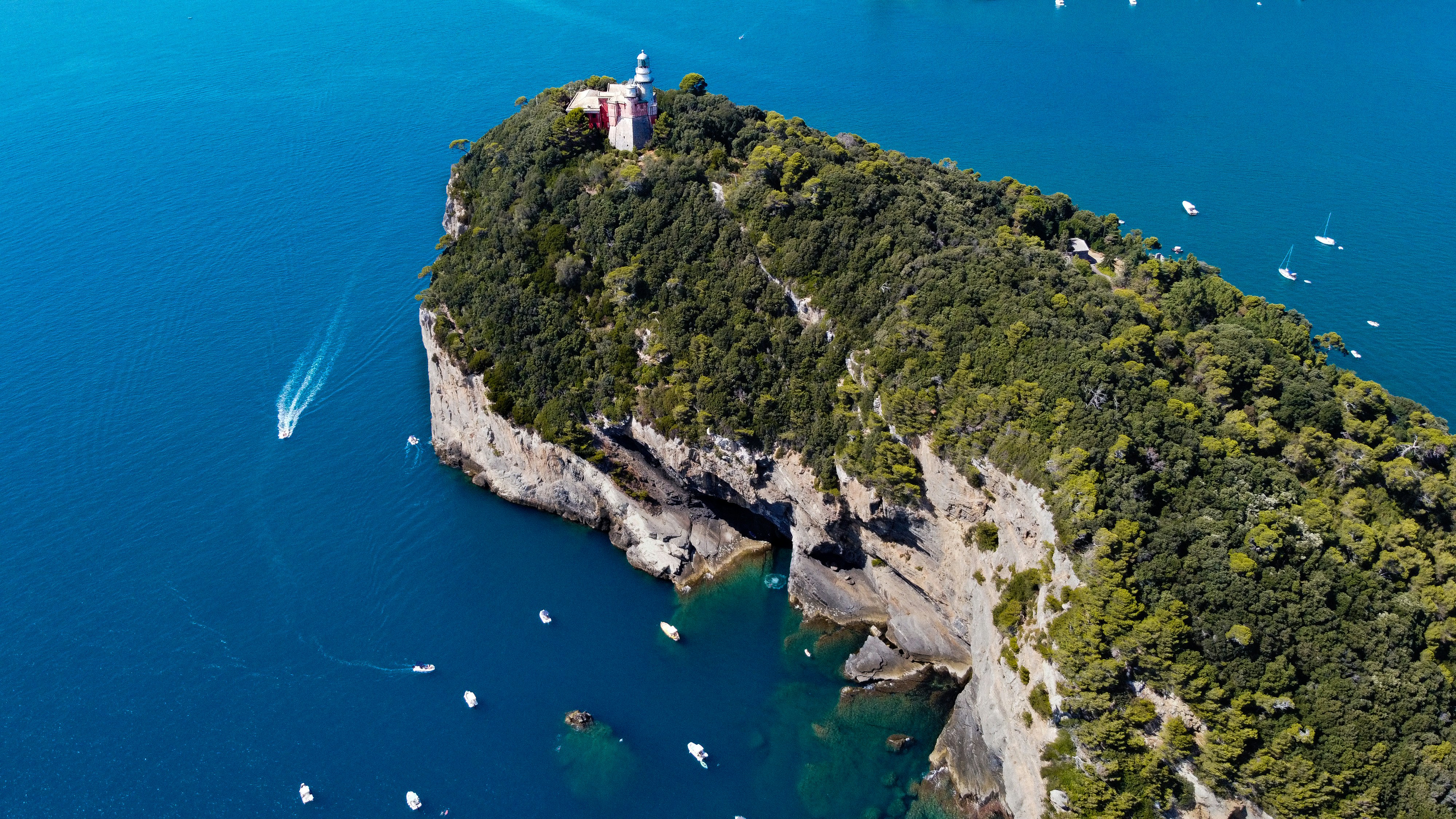 people on green and brown mountain near blue sea during daytime