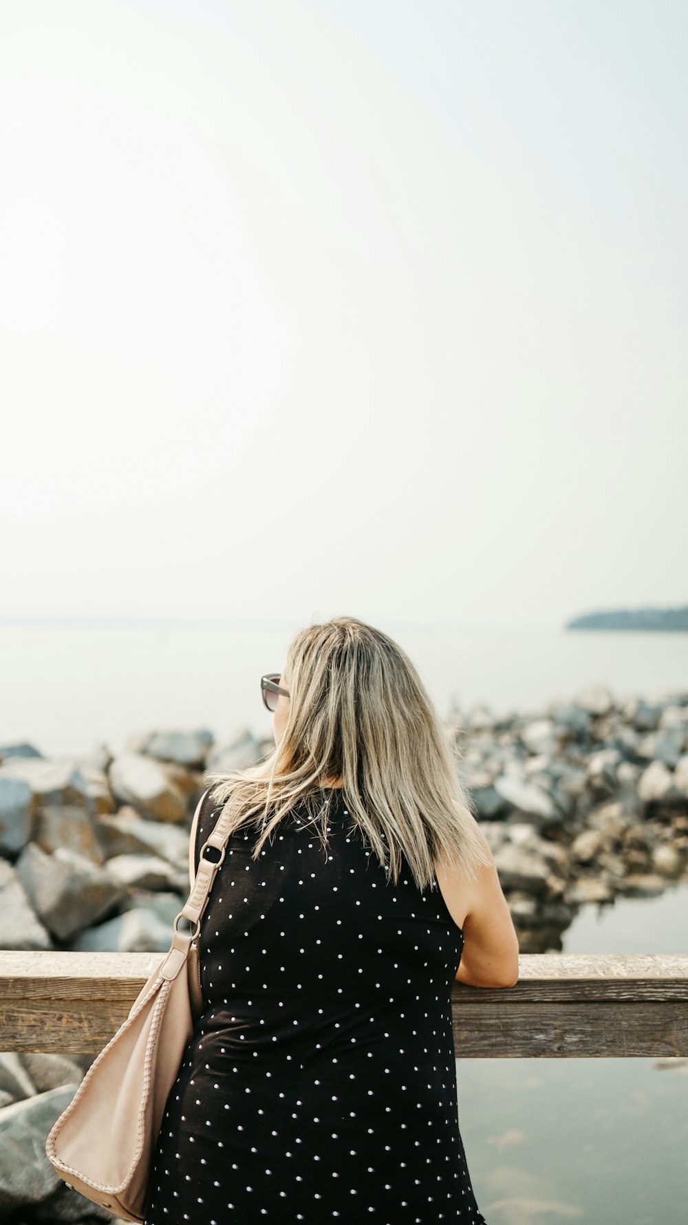 woman in black tank top standing on rocky shore during daytime