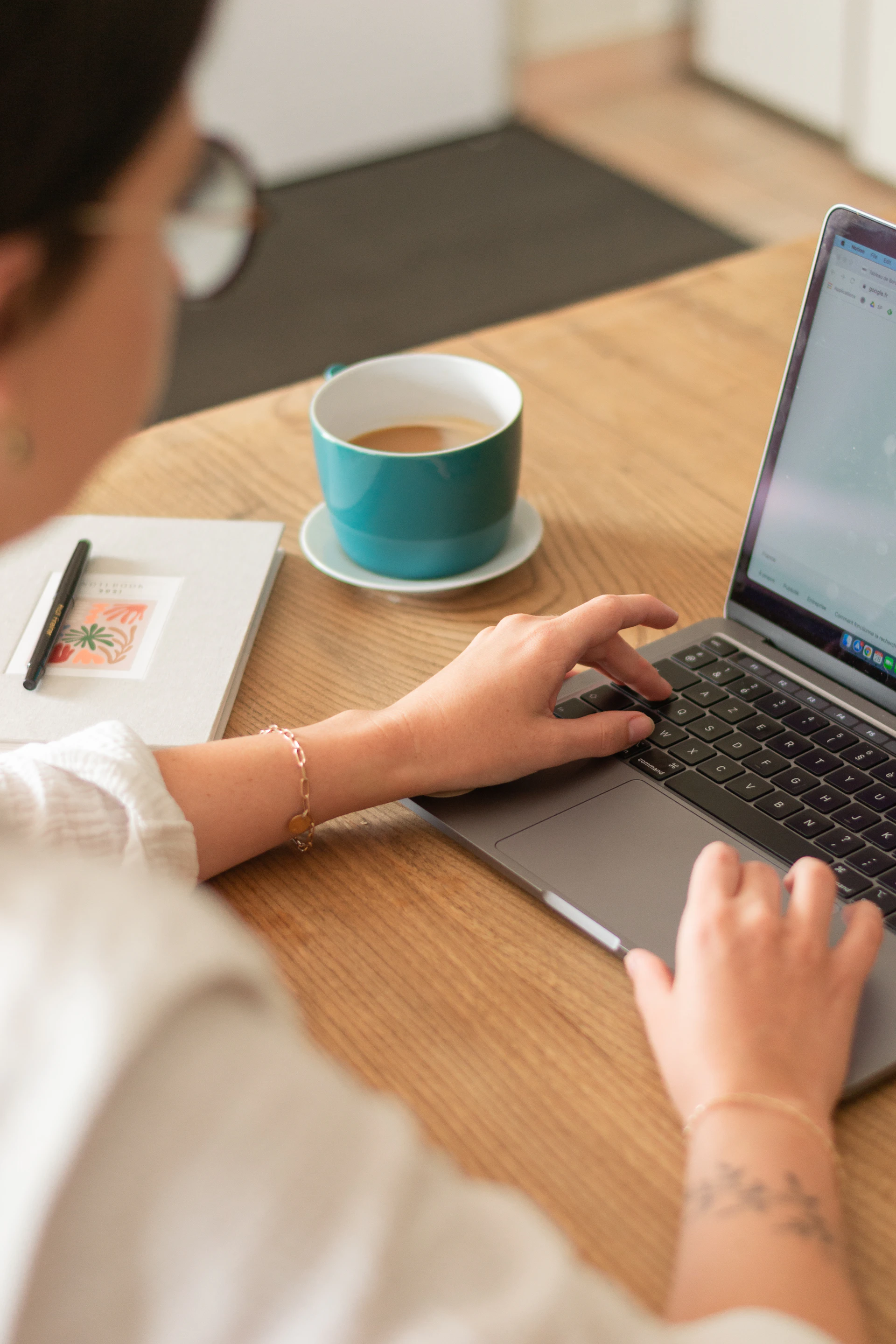 person in white long sleeve shirt using macbook pro on brown wooden table