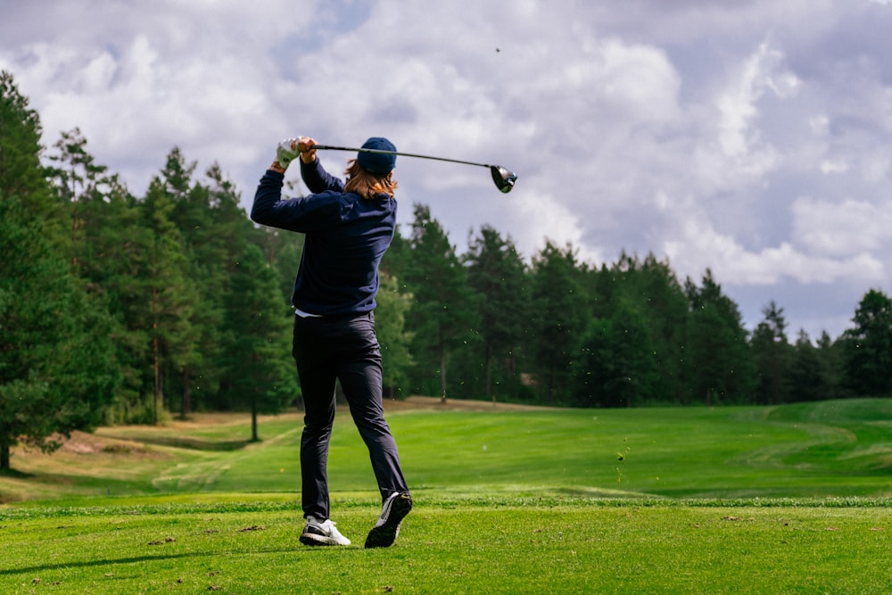 man in black jacket and black pants playing golf during daytime