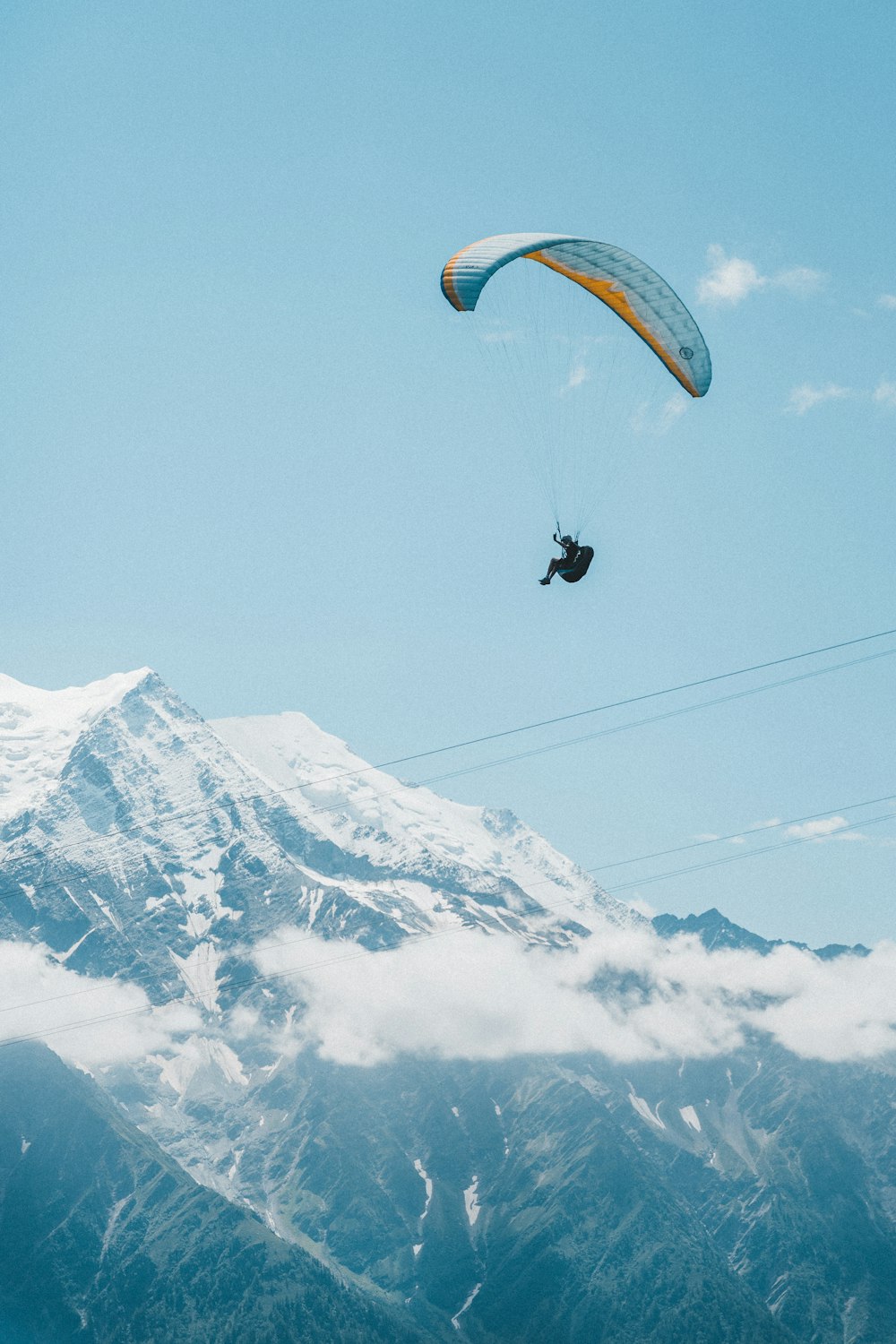 person riding on yellow parachute over snow covered mountain during daytime