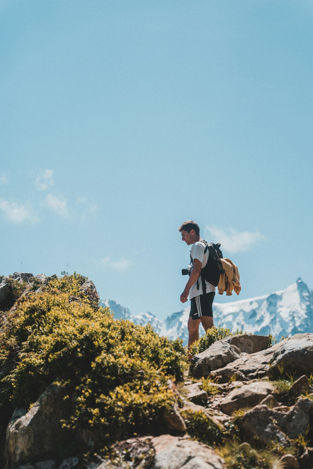 man in black t-shirt and brown shorts standing on rocky mountain during daytime