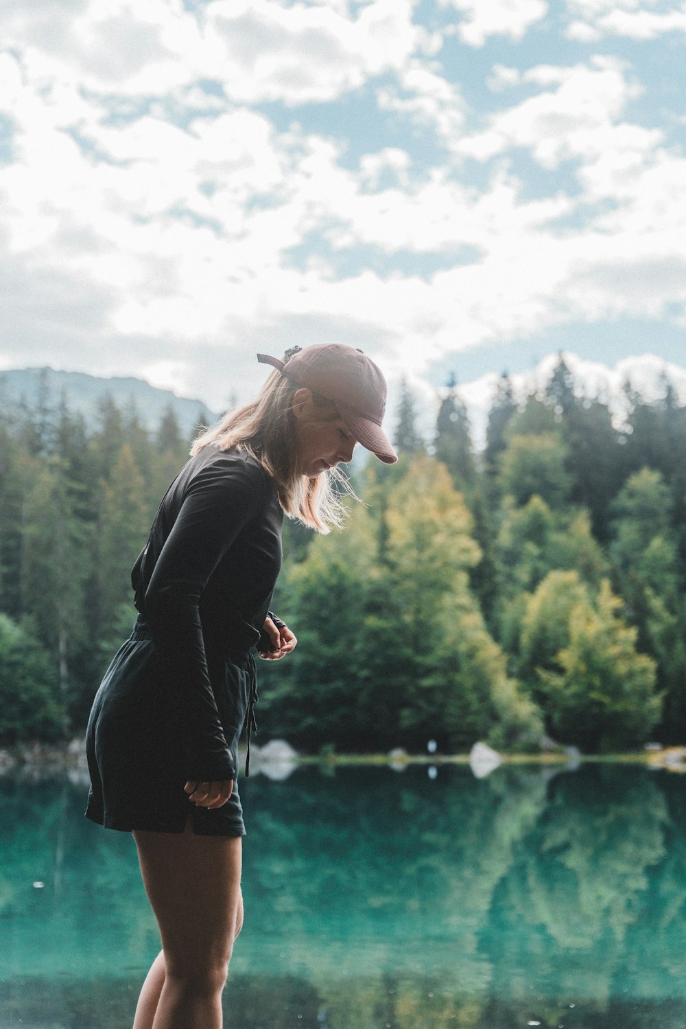 woman in black jacket standing near lake during daytime