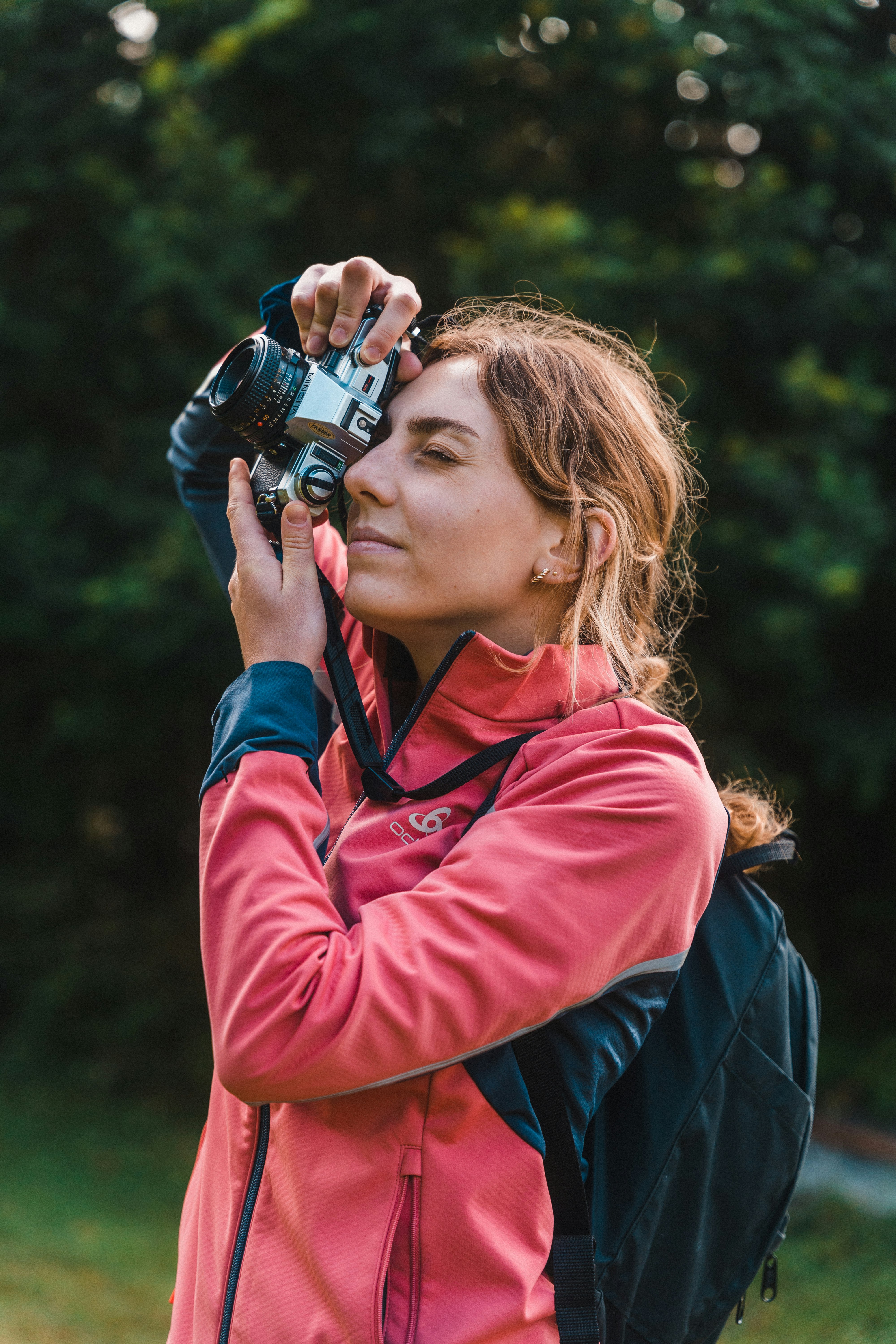 woman in red jacket holding black dslr camera