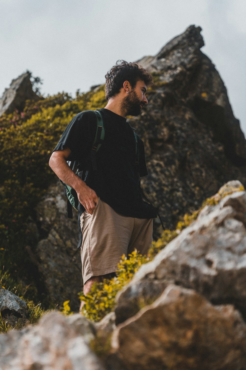man in black t-shirt and beige shorts standing on rock formation during daytime