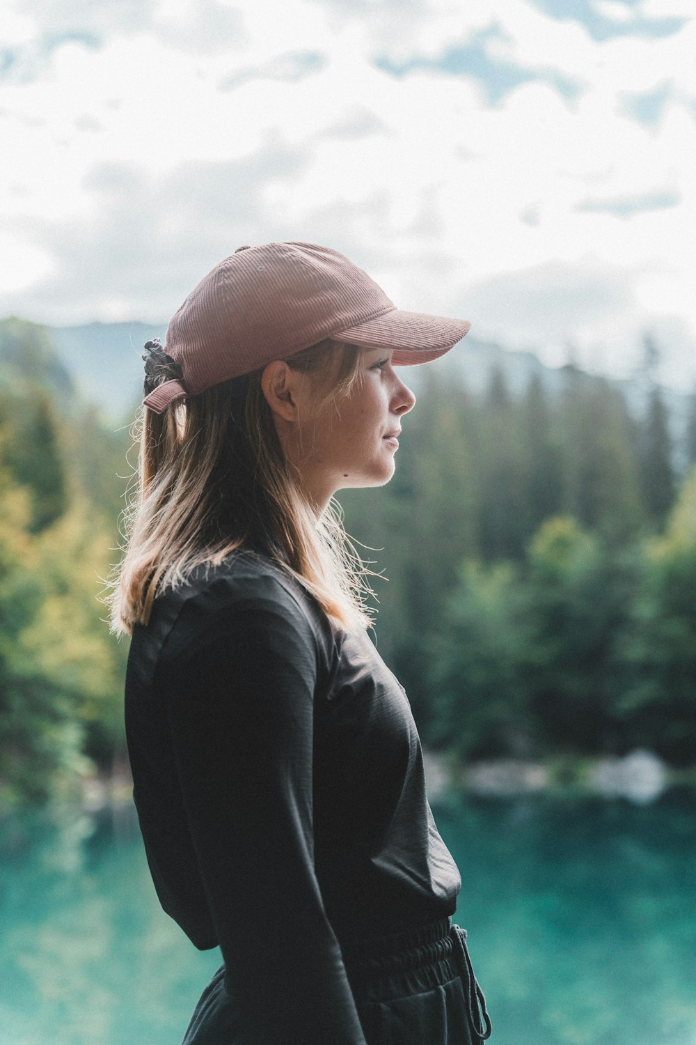 woman in black jacket and brown hat standing near green trees during daytime