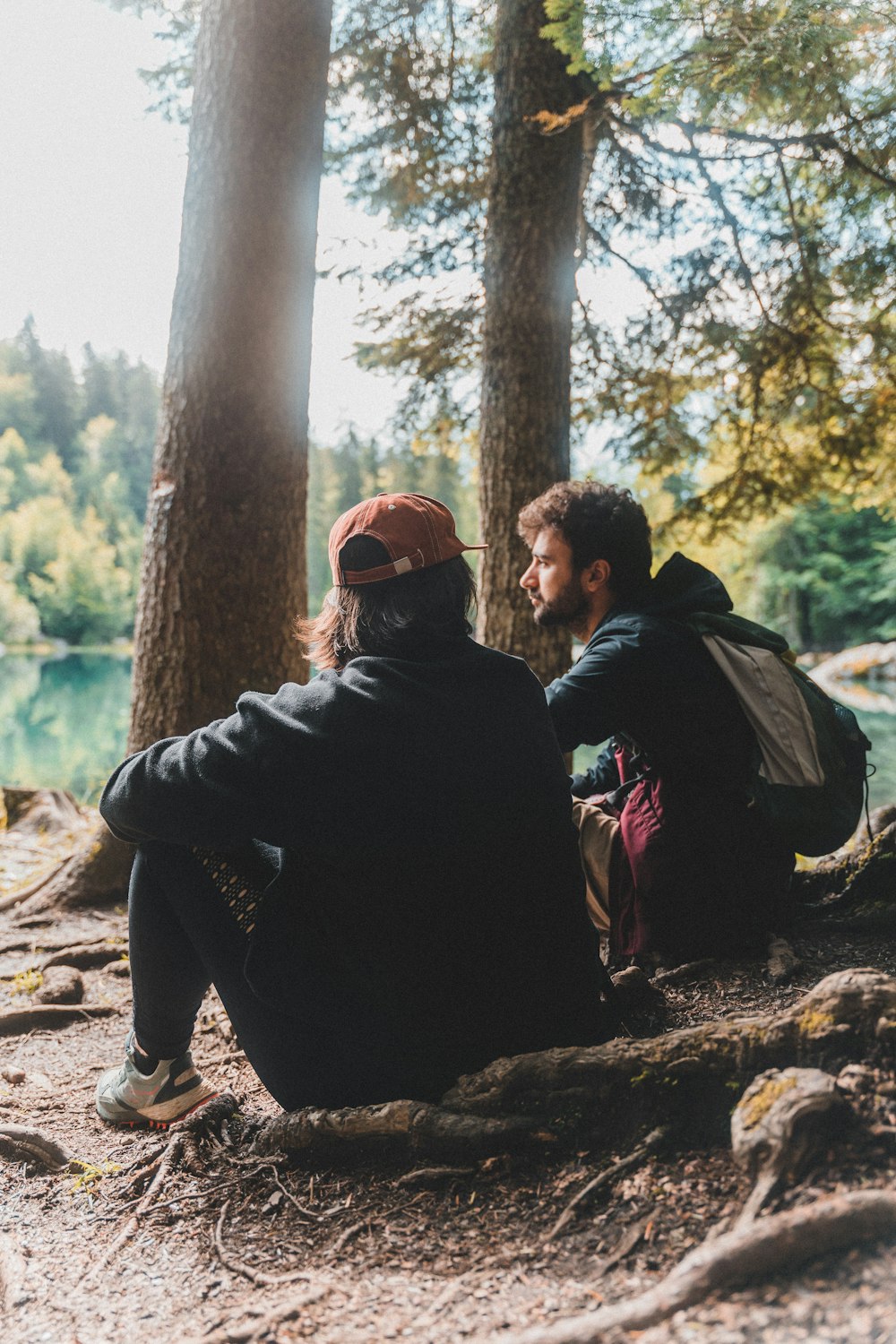 man in black jacket sitting on tree log during daytime