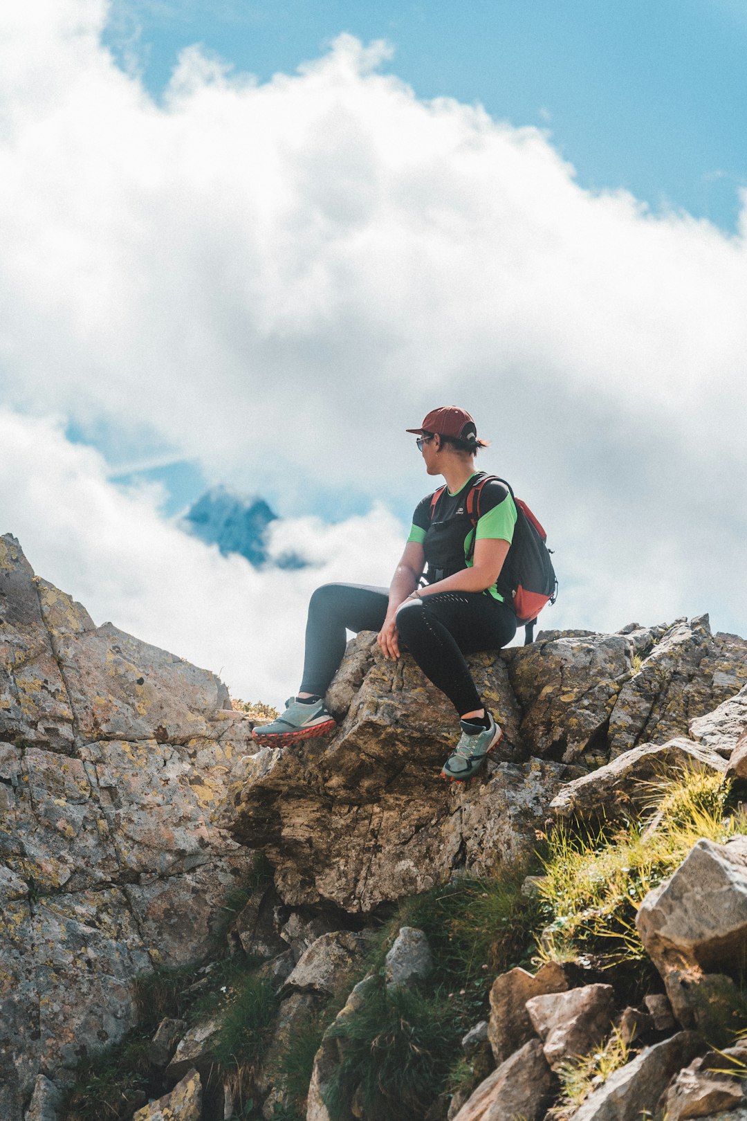 woman in green shirt and blue denim jeans sitting on rock during daytime