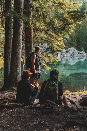 2 women sitting on rock near body of water during daytime