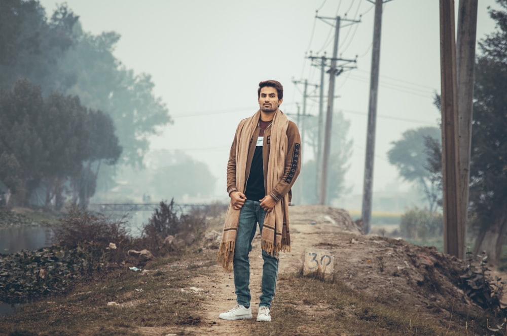 man in brown leather jacket standing on brown field during daytime