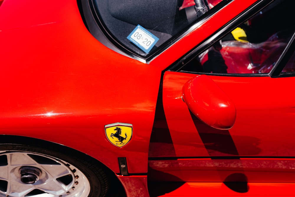 um carro vermelho com um emblema da Ferrari em seu lado