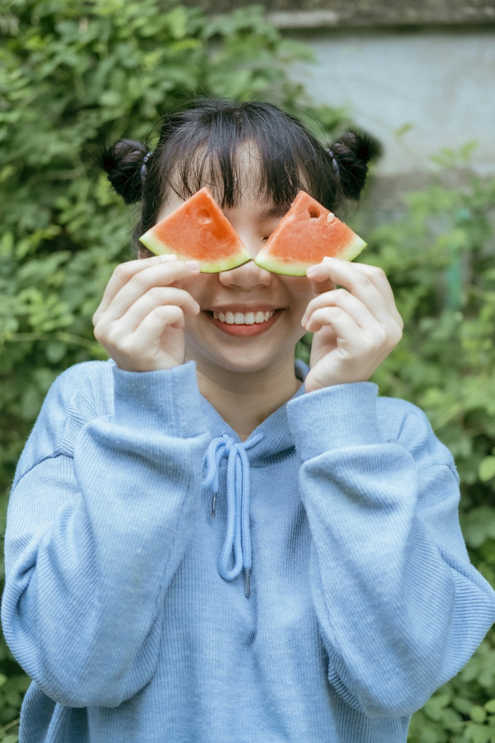 woman in blue hoodie holding sliced watermelon