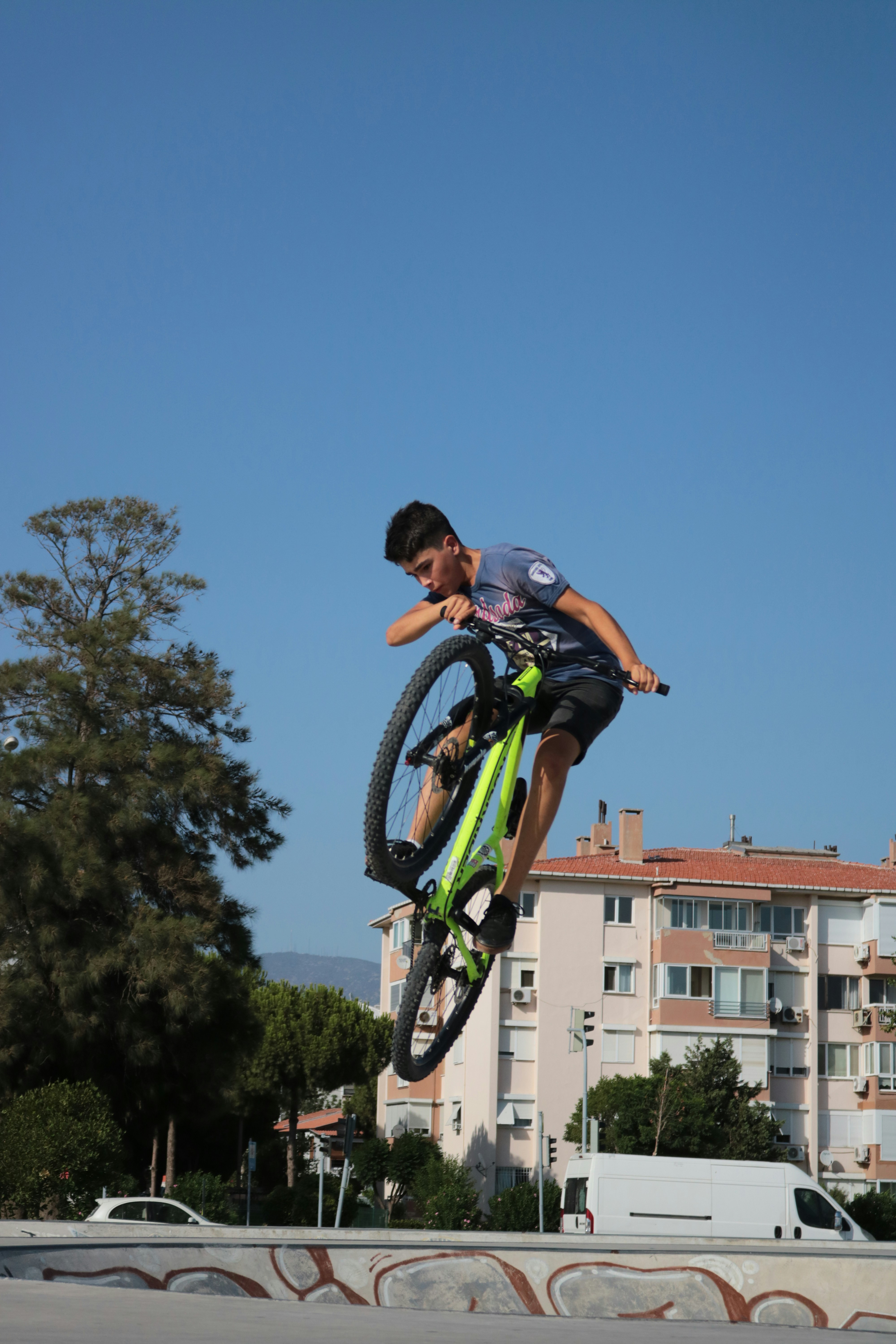 Hombre con camiseta sin mangas azul y blanca montando en bicicleta de montaña verde y negra durante el día