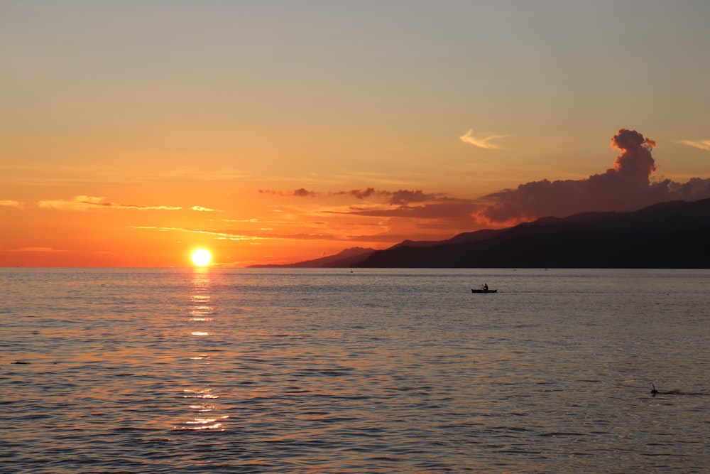 silhouette of boat on sea during sunset