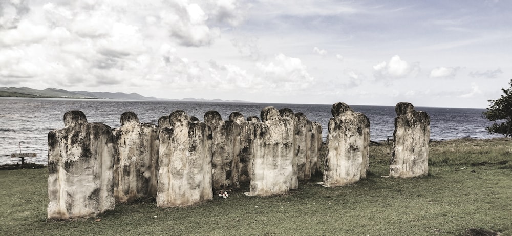 brown rock formation on green grass field under white clouds during daytime