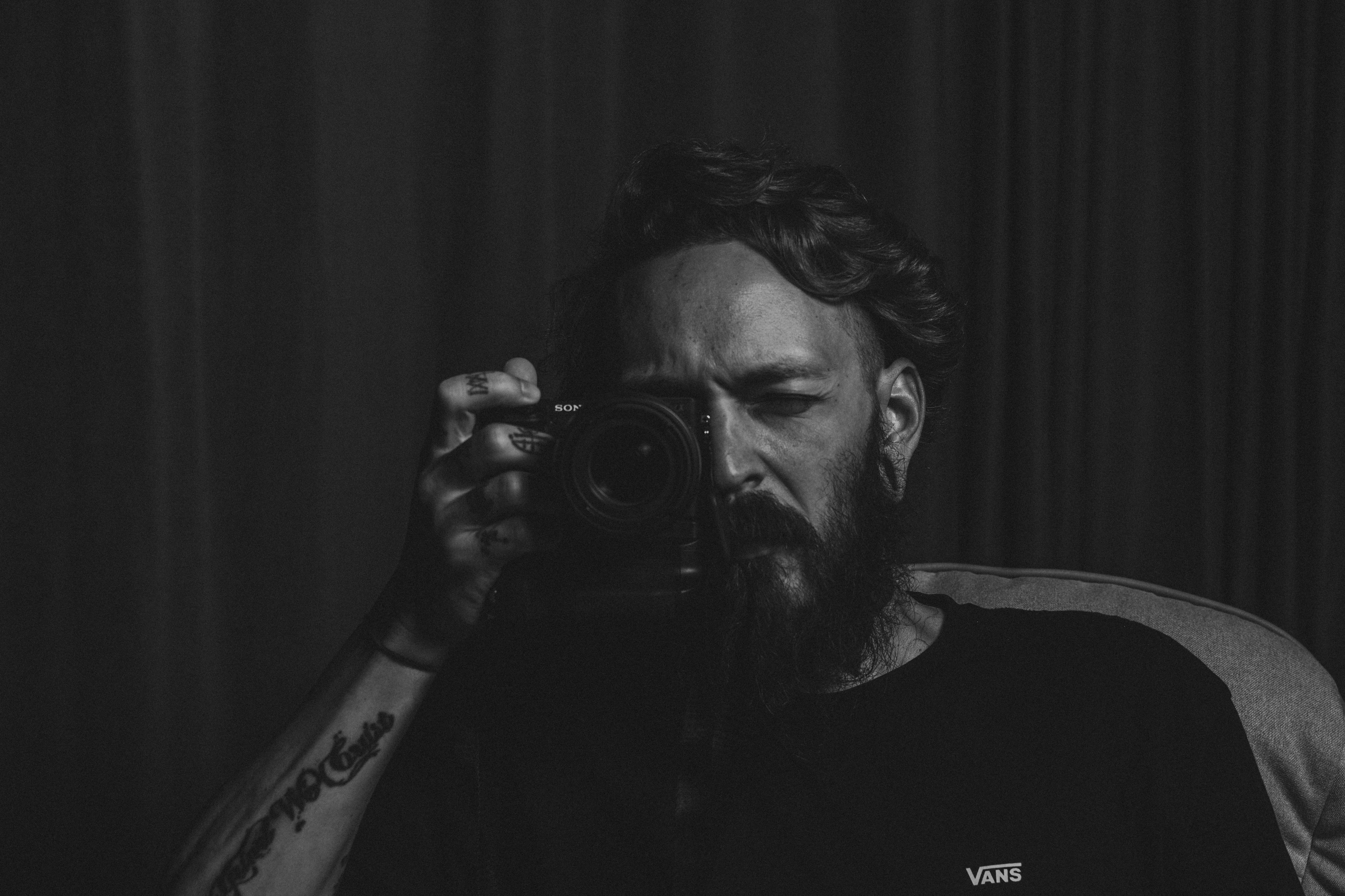 man in black crew neck shirt holding black camera attractive teams background