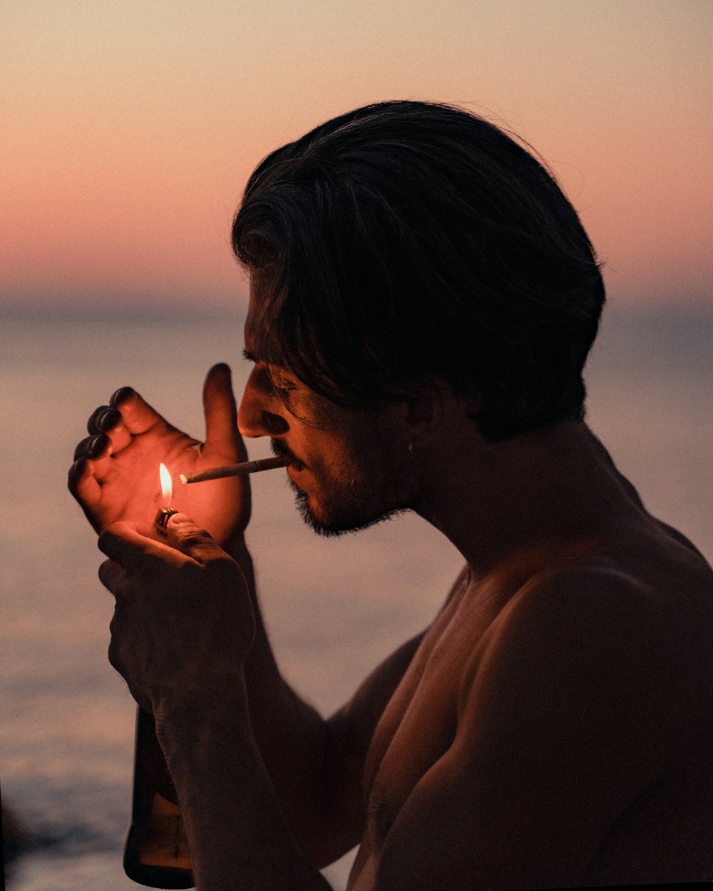 homme fumant une cigarette au coucher du soleil