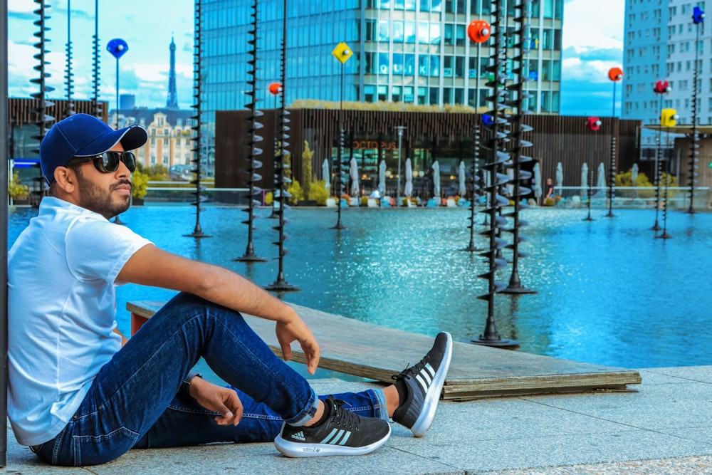 man in blue denim jeans sitting on brown wooden dock during daytime