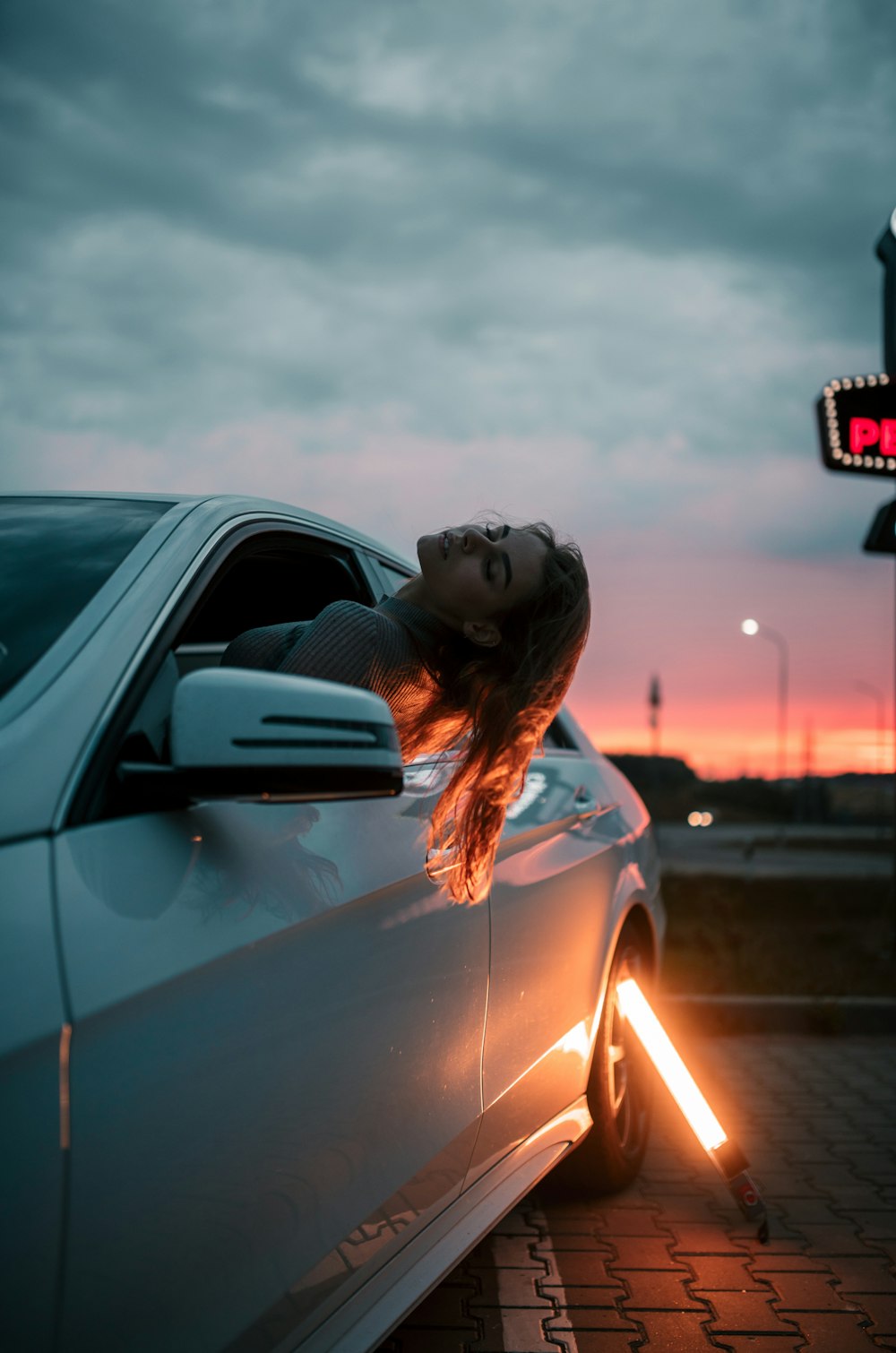 femme en chemise orange assise sur la voiture