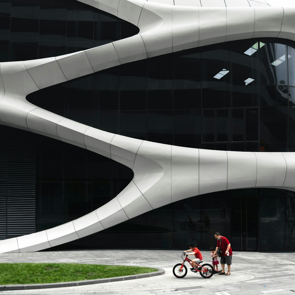 man in red shirt and black pants sitting on white concrete bench