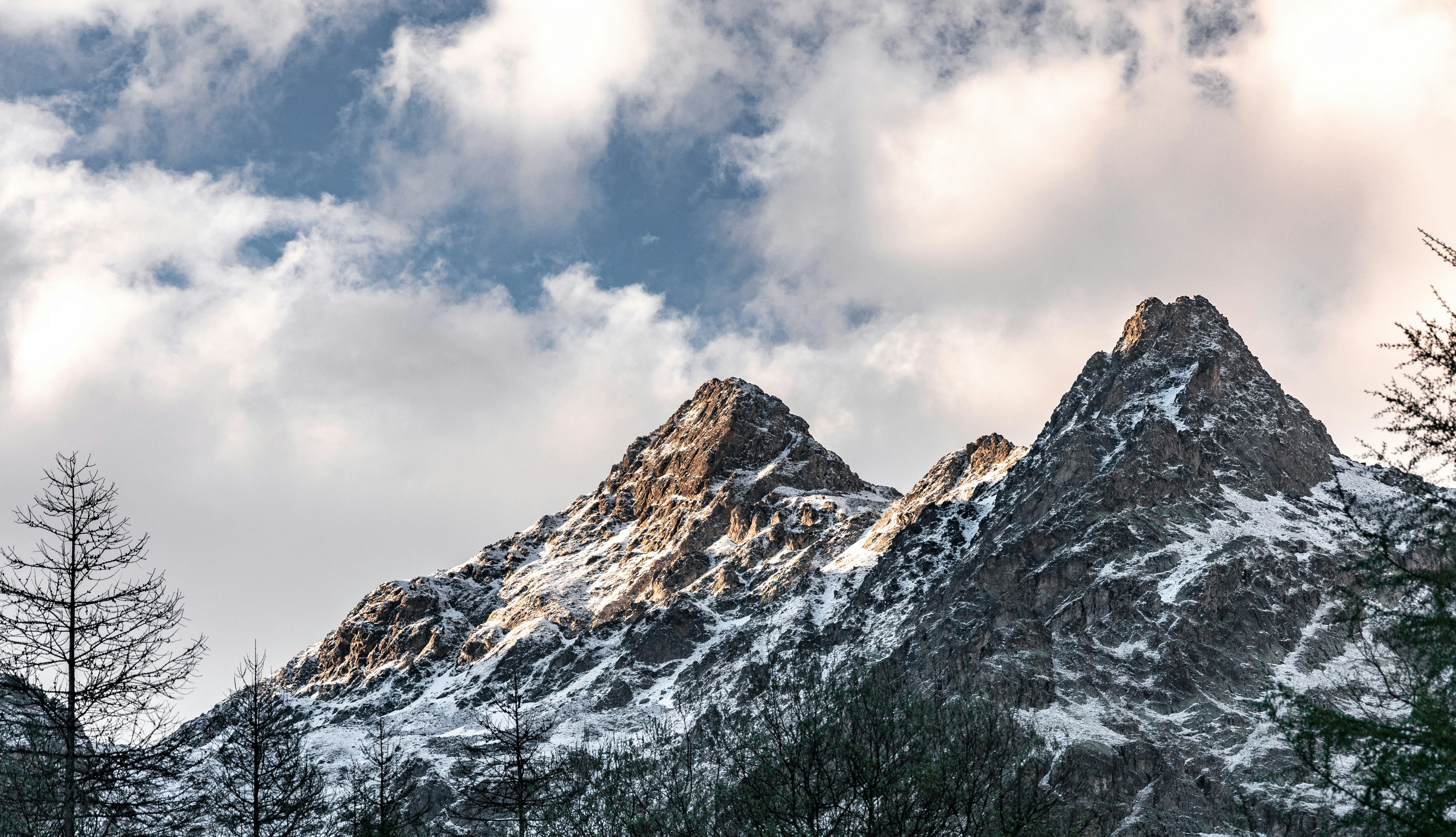 昼間の曇り空の下、雪に覆われた山