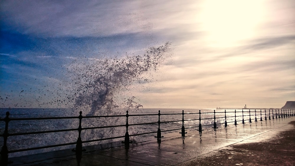 sea waves crashing on wooden dock during sunset